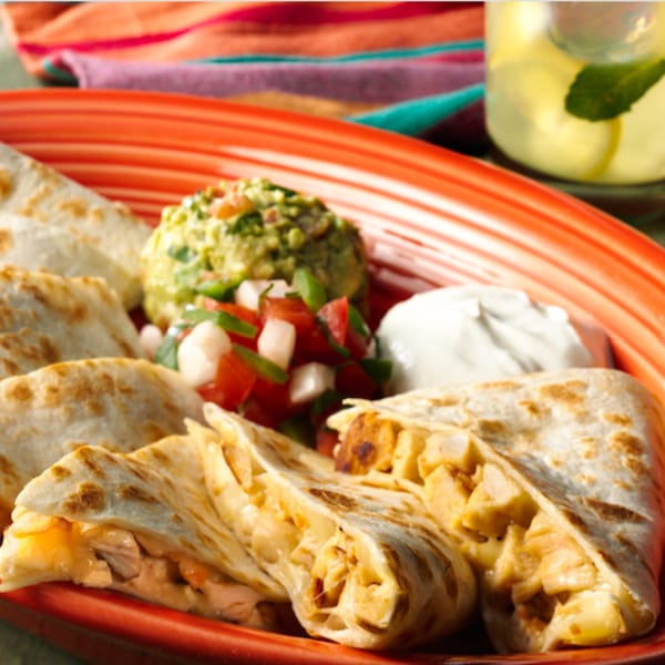 Berryhill Baja Grill quesadillas with guacamole, pico de gallo, and sour cream on a red plate.