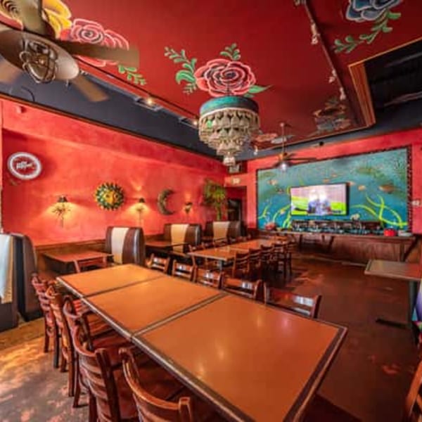 Berryhill Baja Grill's vibrant dining room with red walls, decorative ceiling, and wooden tables and chairs.