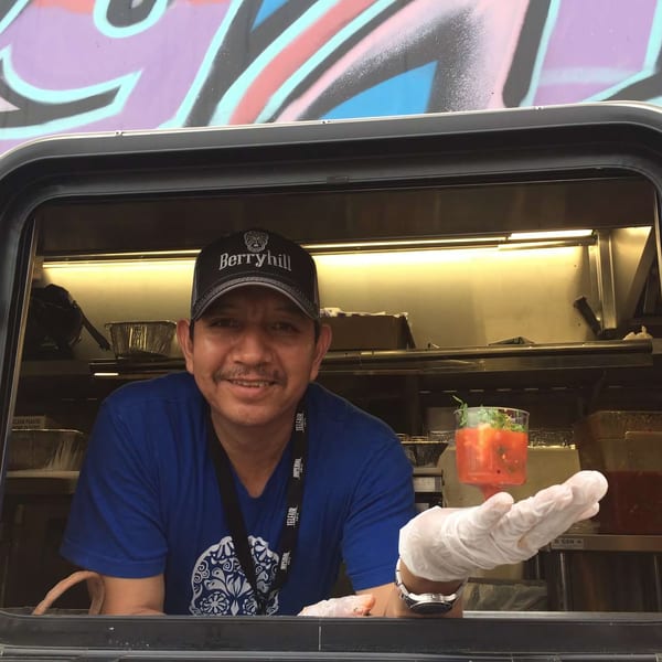 A Berryhill Baja Grill employee in a food truck window holds out a cup of salsa.