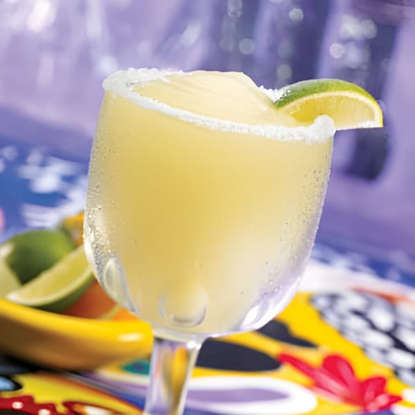 A frosty Berryhill Baja Grill margarita with a salted rim and lime wedge on a colorful table.