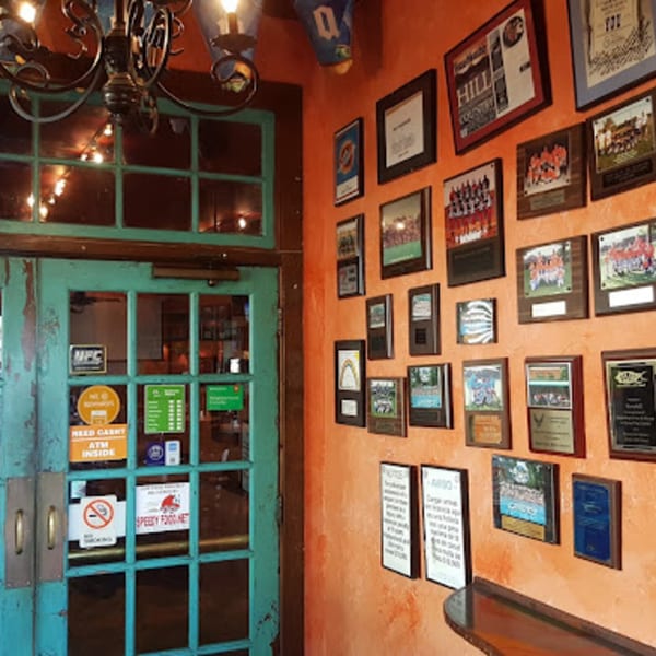 Teal glass doors and an orange wall adorned with framed awards and photos at Berryhill Baja Grill.