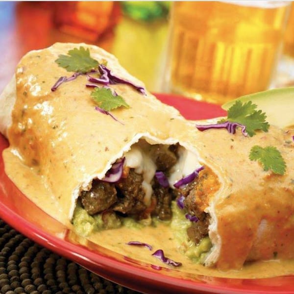 A Berryhill Baja Grill burrito, cut open, revealing meat, guacamole, cheese, and red cabbage.