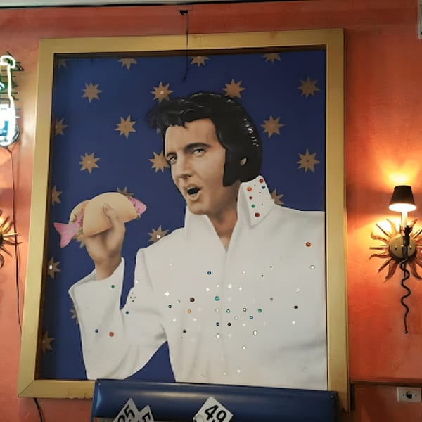 Framed painting of Elvis Presley in a white jumpsuit holding a fish taco, against a starry blue background.