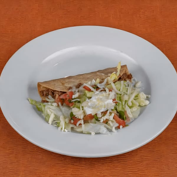 Berryhill Baja Grill's crispy beef taco with lettuce, tomato, cheese, and sour cream on a white plate.