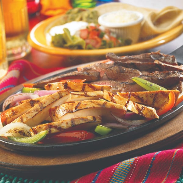 Sizzling Berryhill Baja Grill fajitas with chicken and steak, colorful peppers, onions, and a side of guacamole.