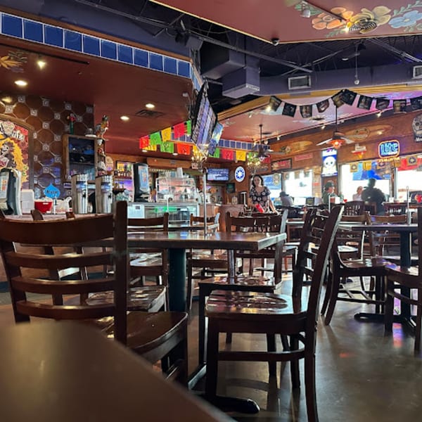 Interior of Berryhill Baja Grill, featuring wooden tables and chairs, a bar area, and festive Mexican decorations.