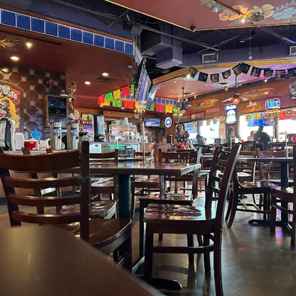 Interior of Berryhill Baja Grill, featuring wooden tables and chairs, a bar area, and festive Mexican decorations.